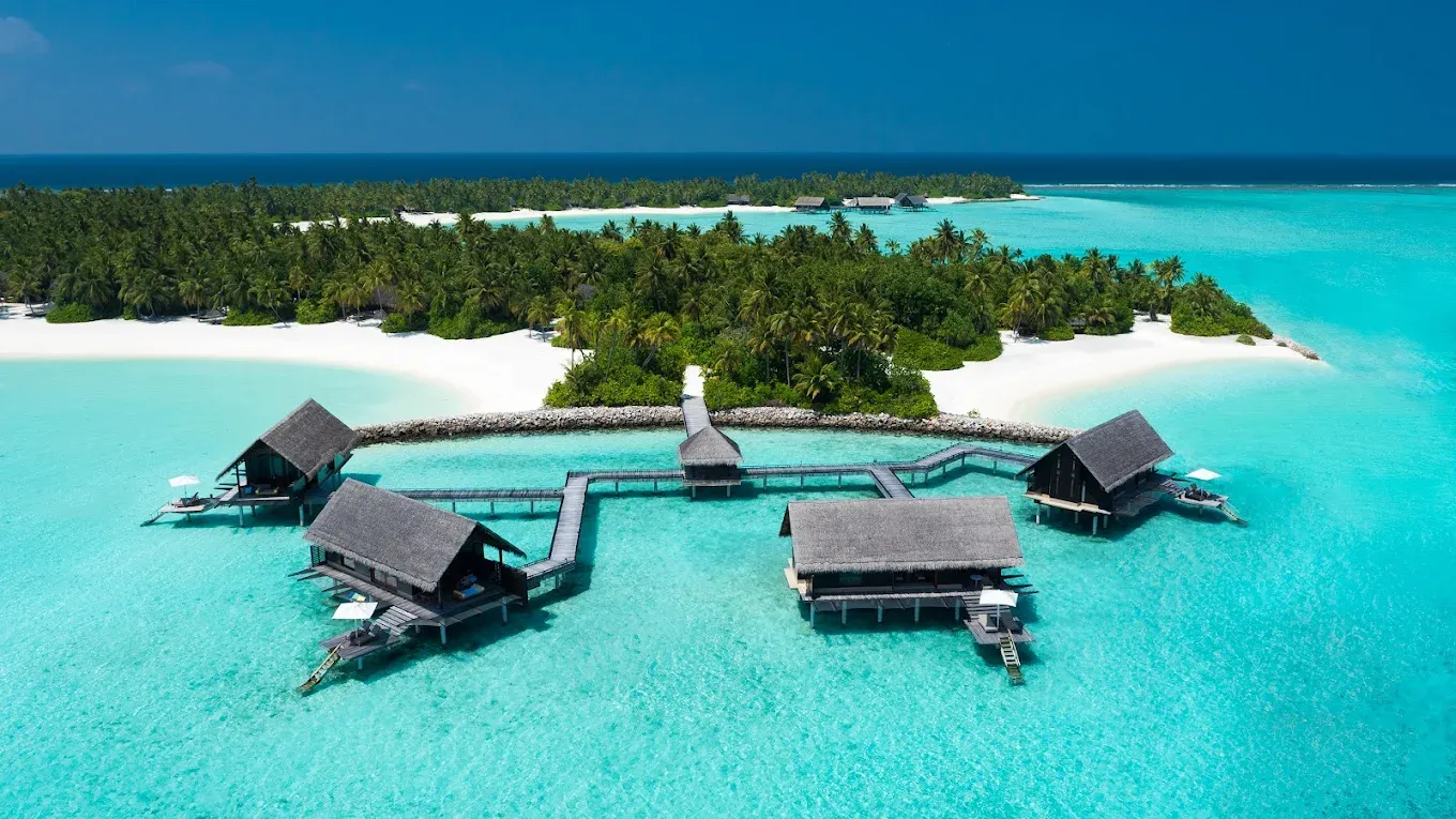 Signature hero of One&Only Reethi Rah (North Malé Atoll, Maldives): the single most iconic wide view — Private island, All-villa resort, Ultra-luxury. Golden-hour, landscape, room to overlay text.