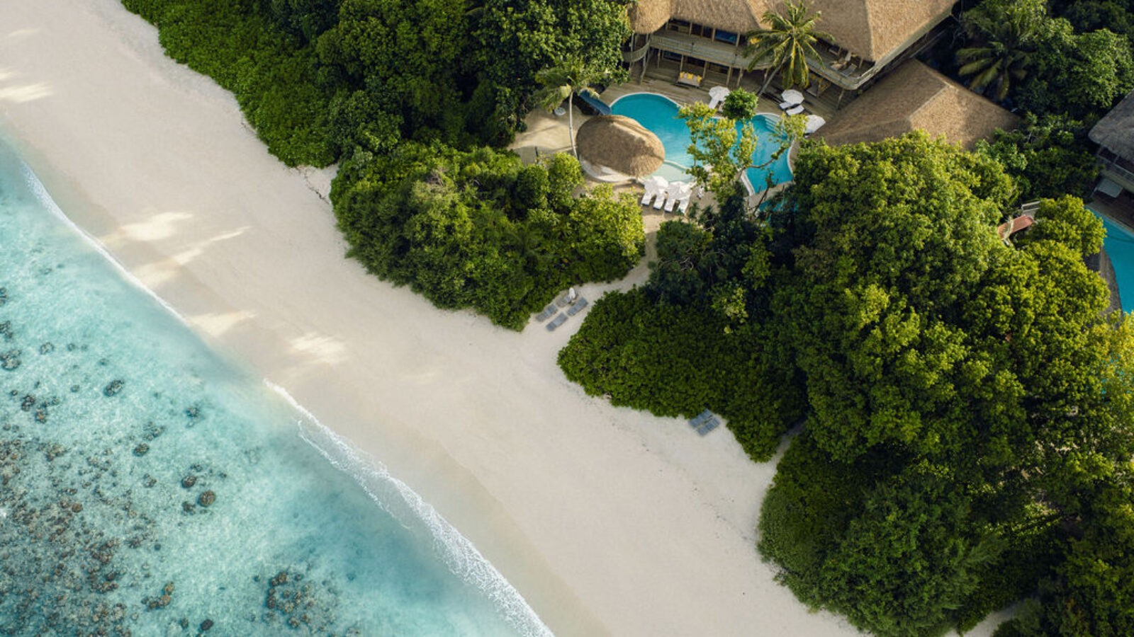 Signature hero of Soneva Fushi (Baa Atoll, Maldives · UNESCO Biosphere Reserve): the single most iconic wide view — Private island, Overwater Water Retreats, Ultra-luxury. Golden-hour, landscape, room to overlay text.